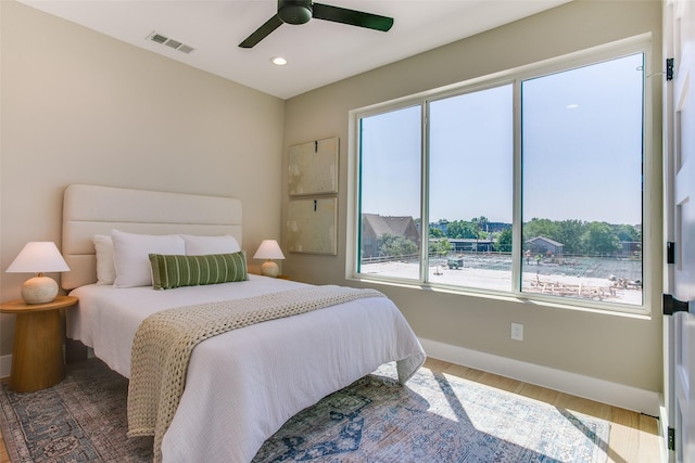 bedroom featuring baseboards, visible vents, multiple windows, and wood finished floors