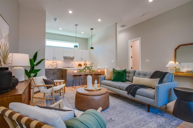 living room with light wood-type flooring, recessed lighting, and visible vents