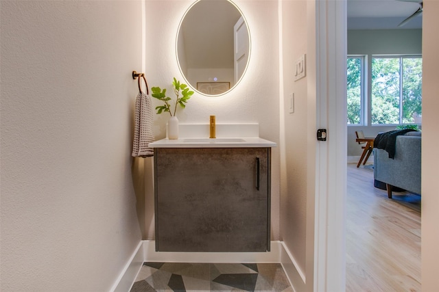bathroom featuring vanity, a textured wall, baseboards, and wood finished floors