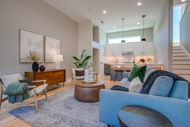 living room with visible vents, stairs, baseboards, light wood-style floors, and recessed lighting