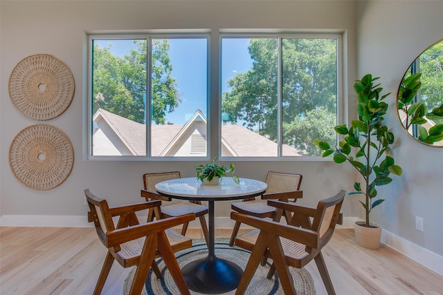 dining area with baseboards and light wood finished floors