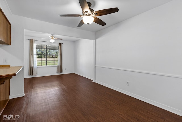 unfurnished living room featuring a ceiling fan, baseboards, and dark wood-type flooring