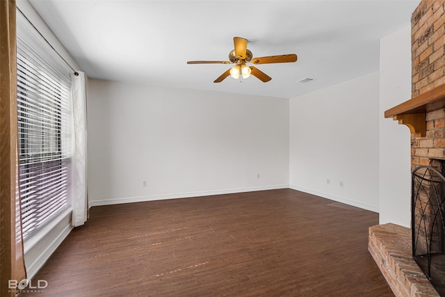 unfurnished living room with ceiling fan, dark wood finished floors, a healthy amount of sunlight, and a fireplace
