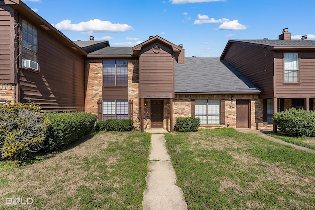 traditional-style house with brick siding, a front yard, and cooling unit