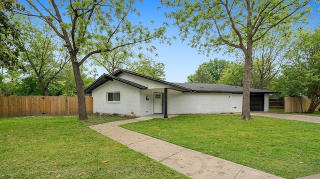 view of front of home with a garage, fence, a front yard, and concrete driveway