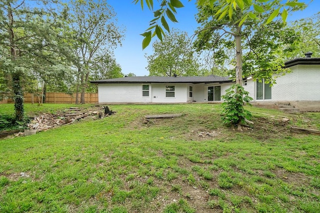 rear view of property with a lawn and fence