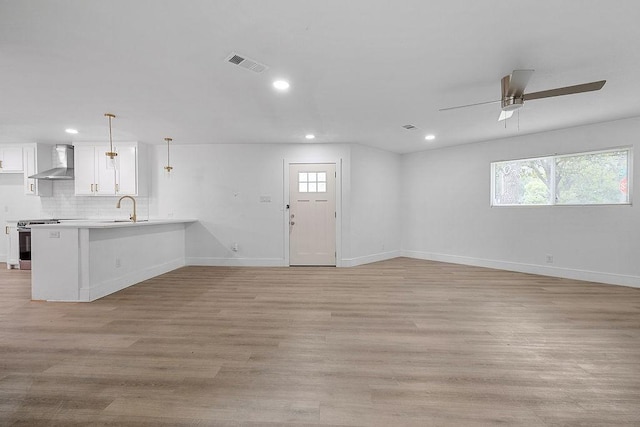 unfurnished living room featuring visible vents, a sink, baseboards, and recessed lighting