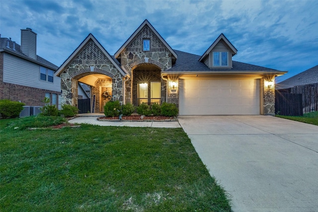 view of front of property featuring a front yard, fence, concrete driveway, an attached garage, and stone siding