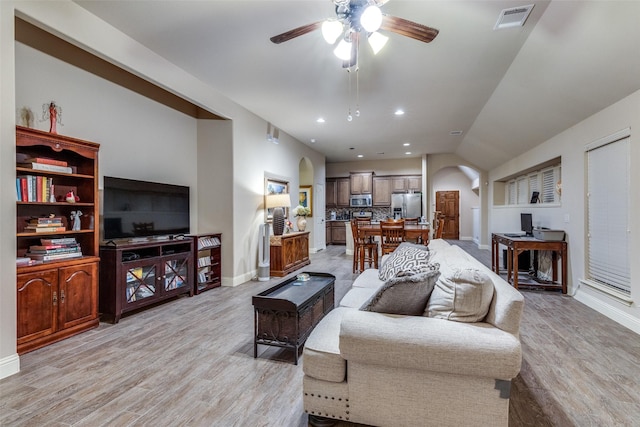 living area featuring light wood-style floors, arched walkways, a ceiling fan, baseboards, and visible vents