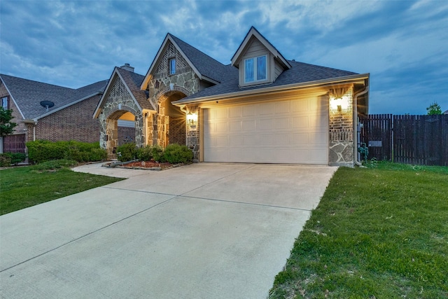 view of front of property featuring fence, a front yard, stone siding, and concrete driveway