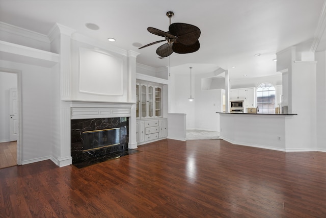 unfurnished living room with ceiling fan, a premium fireplace, recessed lighting, baseboards, and wood finished floors