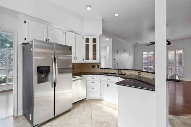 kitchen featuring dark countertops, a sink, stainless steel appliances, a peninsula, and ornamental molding