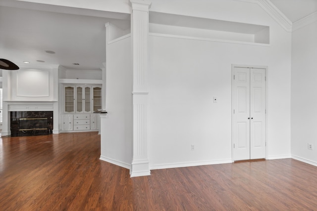 unfurnished living room featuring crown molding, a high end fireplace, ornate columns, and wood finished floors