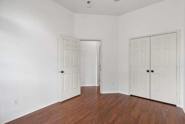 unfurnished bedroom featuring baseboards, dark wood finished floors, and a closet