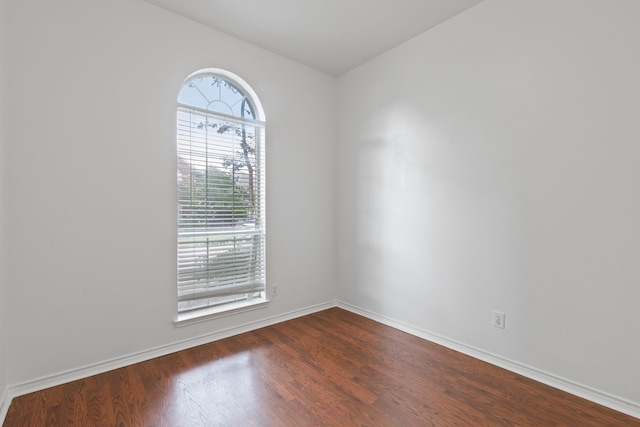 empty room with baseboards and dark wood-type flooring