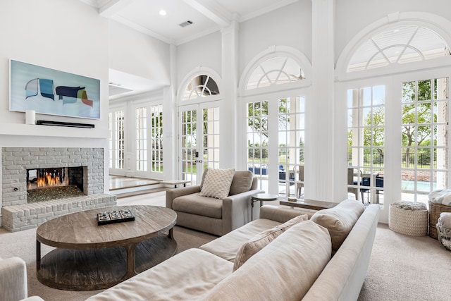 living room featuring a healthy amount of sunlight, a high ceiling, a fireplace, and ornamental molding