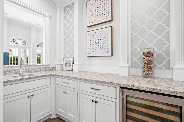 bar with a sink, crown molding, and wine cooler
