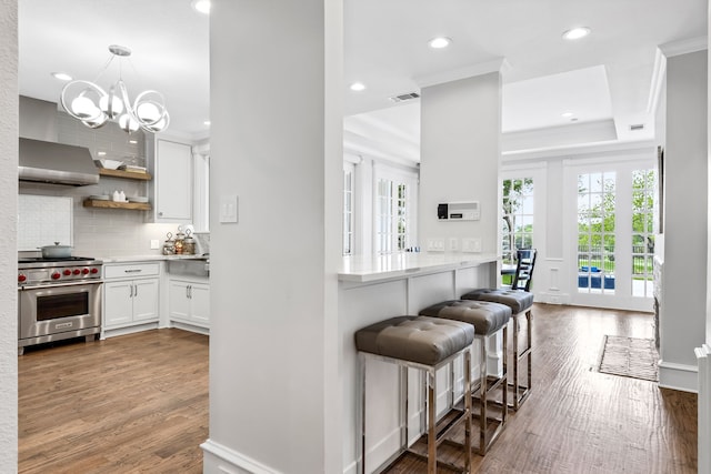 kitchen with visible vents, decorative backsplash, recessed lighting, white cabinets, and premium range