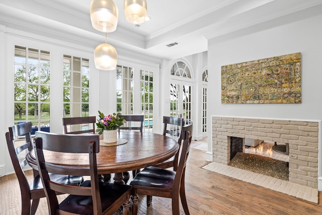 dining area with crown molding, french doors, wood finished floors, a tray ceiling, and visible vents