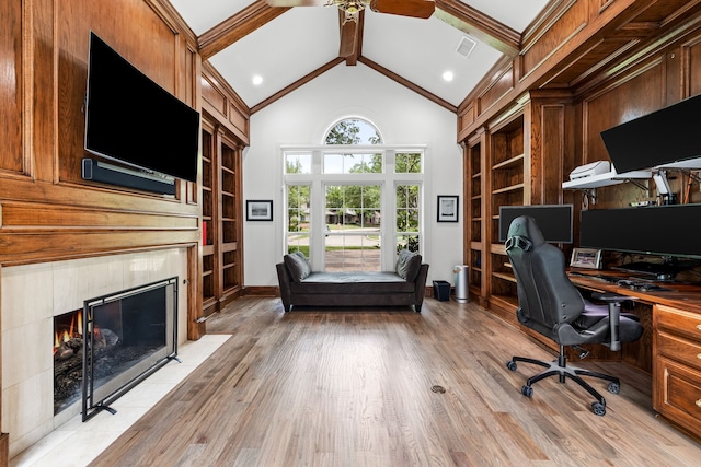 office space featuring visible vents, ceiling fan, built in shelves, light wood-style flooring, and a premium fireplace