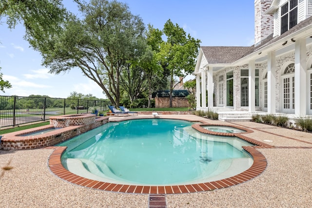 view of pool with fence, a patio, and a pool with connected hot tub