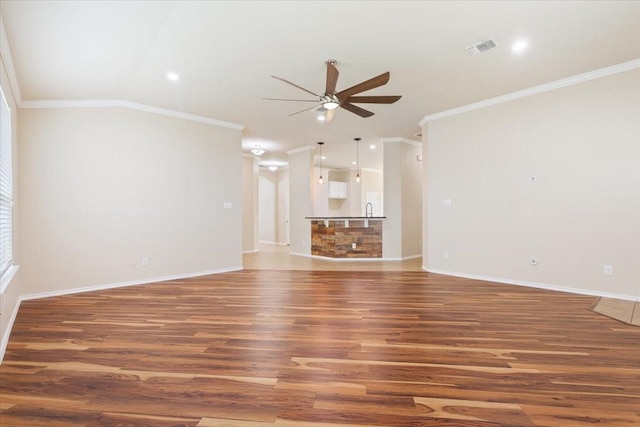 unfurnished living room with visible vents, crown molding, wood finished floors, baseboards, and a ceiling fan