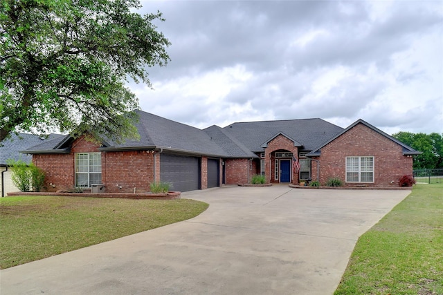 ranch-style home featuring a shingled roof, an attached garage, a front lawn, brick siding, and concrete driveway