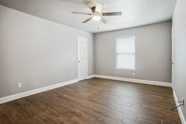 empty room with baseboards, ceiling fan, a textured ceiling, and dark wood-type flooring