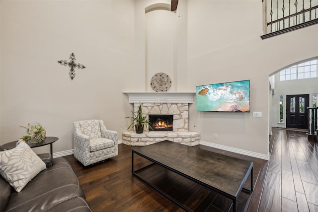 living room with baseboards, arched walkways, a fireplace, and hardwood / wood-style flooring