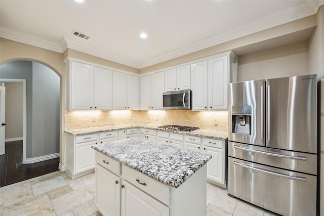 kitchen featuring light stone counters, arched walkways, stainless steel appliances, tasteful backsplash, and visible vents