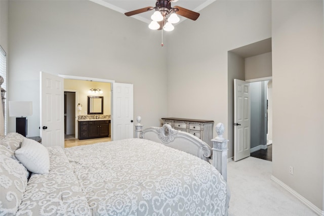 bedroom with crown molding, baseboards, a high ceiling, light colored carpet, and ensuite bath