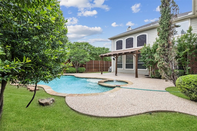 view of swimming pool with fence, a yard, a patio area, and a pool with connected hot tub