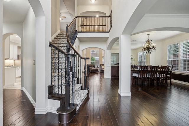 foyer entrance with stairs, dark wood-style flooring, baseboards, and ceiling fan with notable chandelier