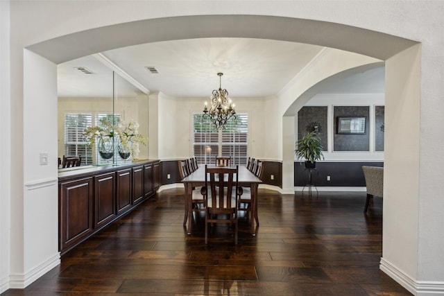 dining room featuring crown molding, visible vents, dark wood-style floors, and a notable chandelier
