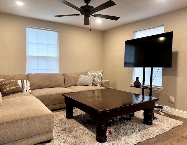 living room featuring baseboards, ceiling fan, wood finished floors, and a wealth of natural light