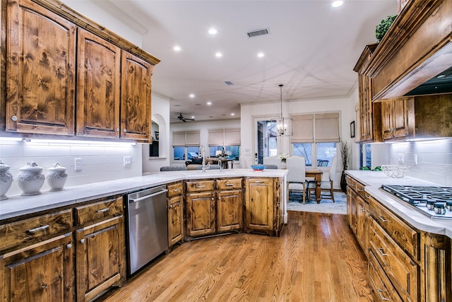kitchen featuring decorative backsplash, visible vents, a peninsula, stainless steel appliances, and light wood-style flooring