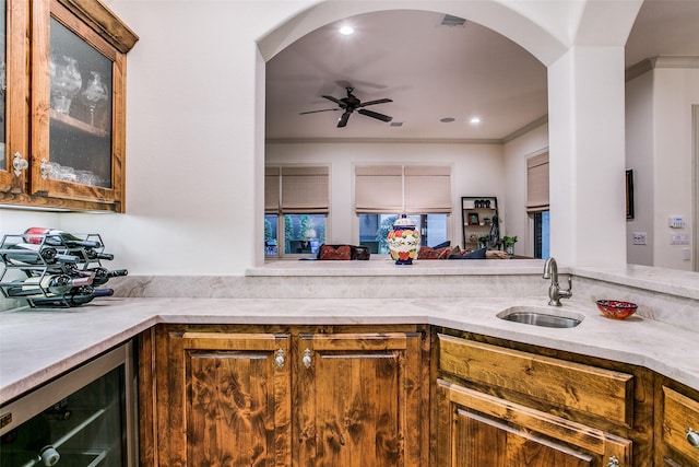 bar featuring crown molding, wine cooler, ceiling fan, arched walkways, and a sink