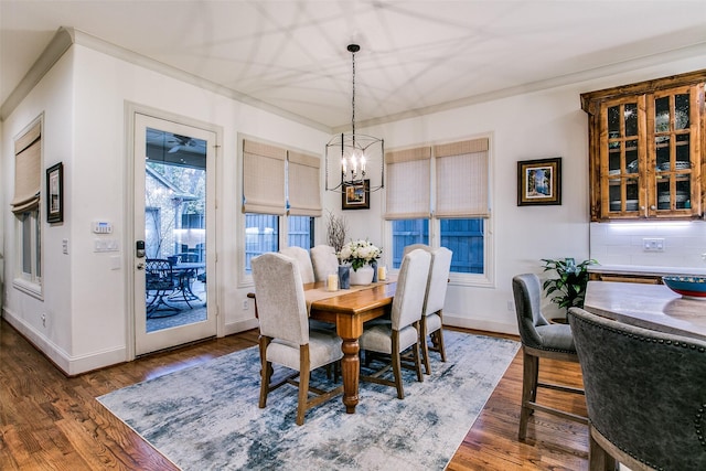 dining space featuring an inviting chandelier, ornamental molding, baseboards, and wood finished floors