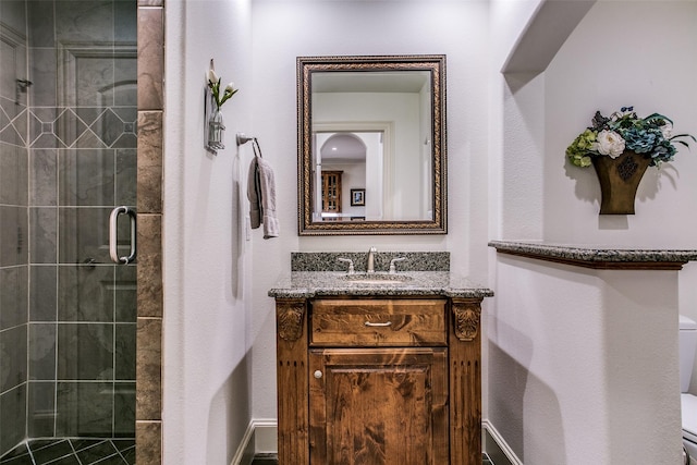 bathroom with vanity, a shower stall, and toilet