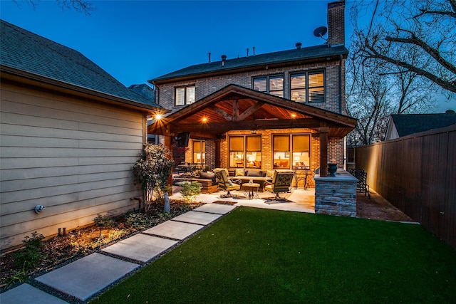 back of property with brick siding, a fenced backyard, an outdoor living space, a patio area, and a lawn
