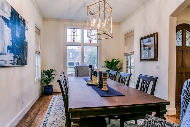 dining area with crown molding, a notable chandelier, wood finished floors, and a healthy amount of sunlight