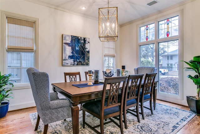 dining room with visible vents, baseboards, an inviting chandelier, ornamental molding, and light wood-style flooring