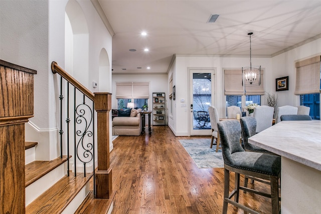 dining room with visible vents, crown molding, stairs, an inviting chandelier, and wood finished floors