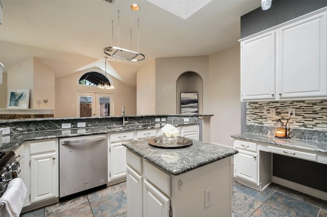 kitchen with stainless steel appliances, a sink, decorative backsplash, a center island, and white cabinetry