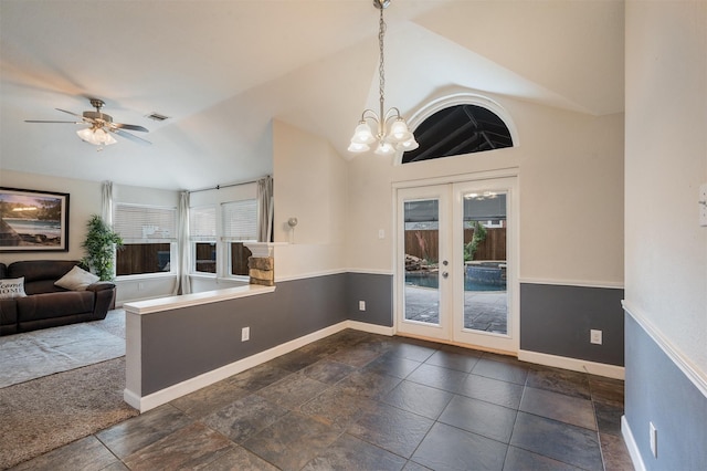 unfurnished dining area with french doors, baseboards, ceiling fan, vaulted ceiling, and a chandelier