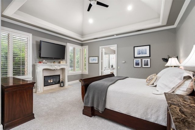 carpeted bedroom with a raised ceiling, a premium fireplace, and multiple windows