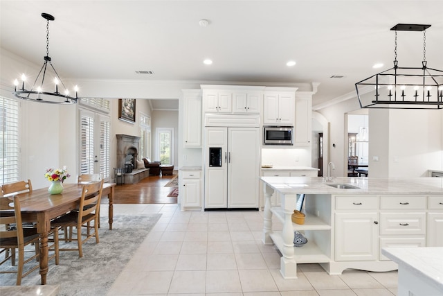 kitchen featuring crown molding, open shelves, a sink, built in appliances, and a chandelier