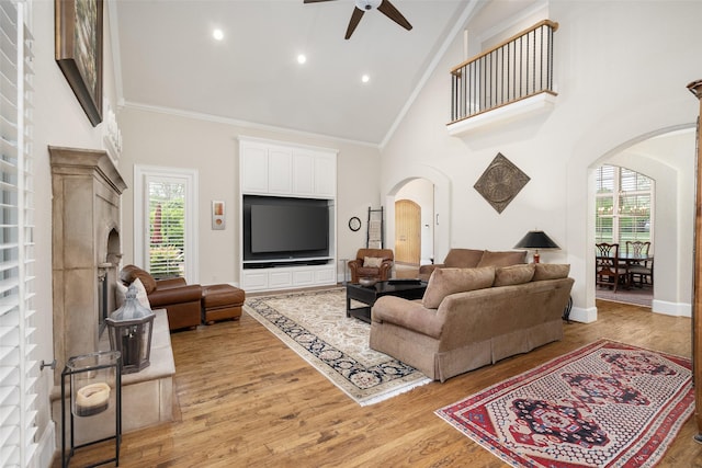 living room featuring arched walkways, ceiling fan, high vaulted ceiling, and a wealth of natural light