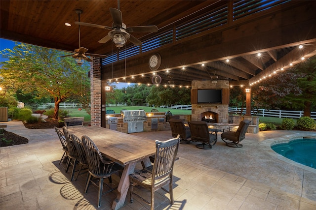view of patio featuring an outdoor stone fireplace, fence, area for grilling, and outdoor dining space