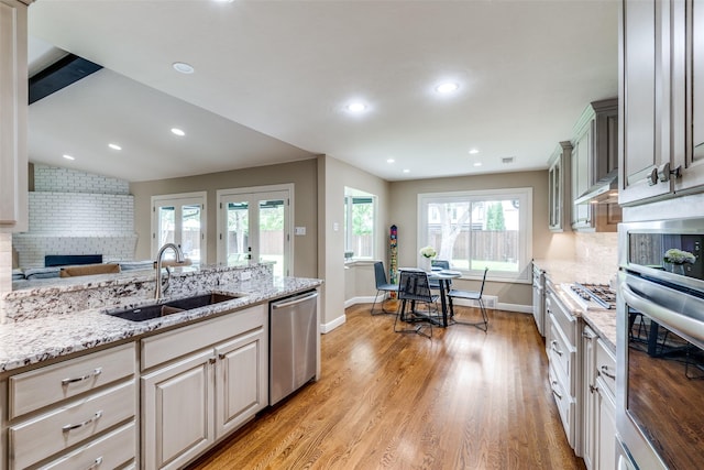 10907 Wonderland Trl, Dallas, TX 75229 - kitchen featuring light wood-style floors, light stone counters, a sink, backsplash, and stainless steel appliances